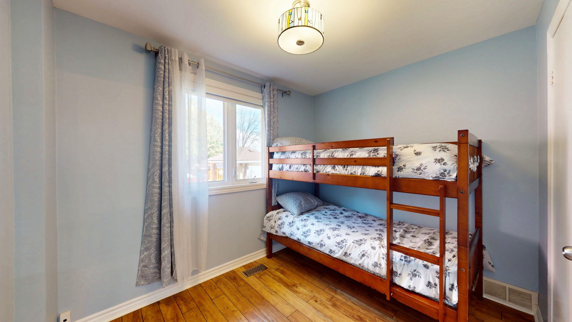 Wood bunk beds with patterned blue sheets in a light blue bedroom