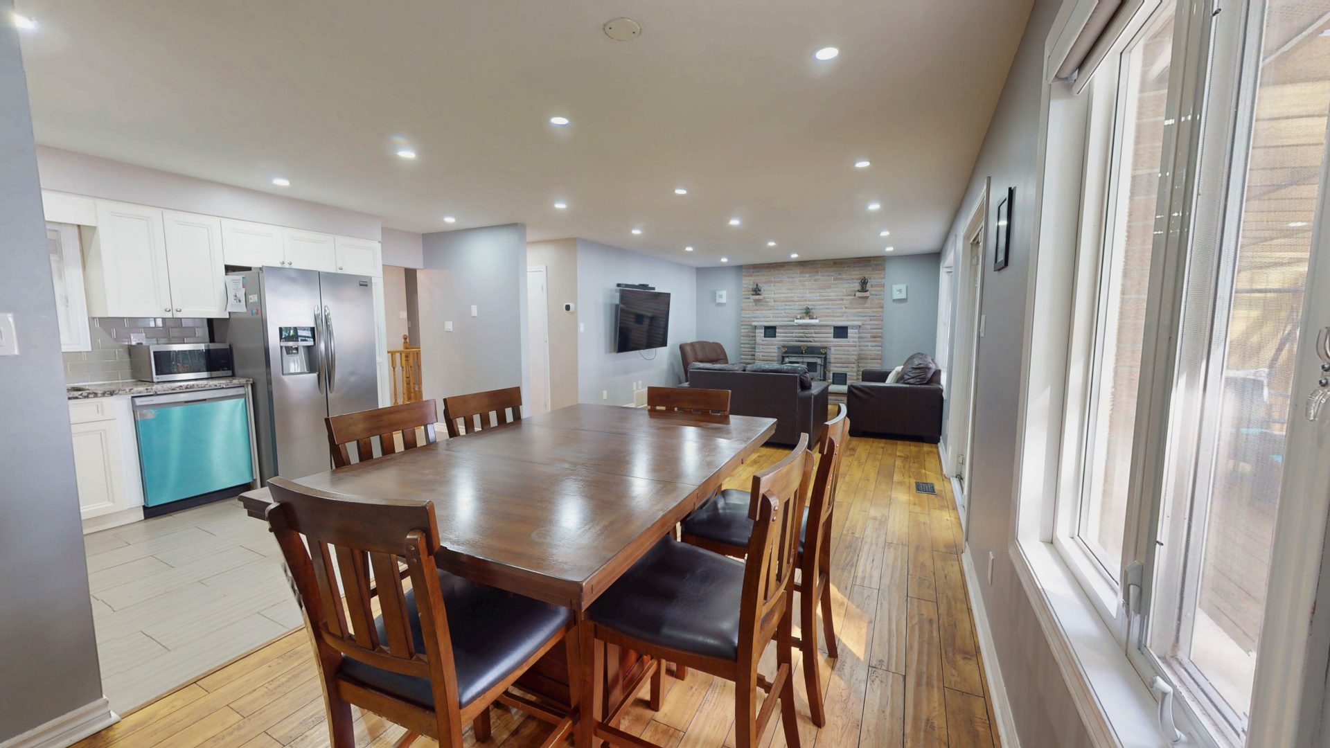 A dark wood dining table across from a living area with grey couches