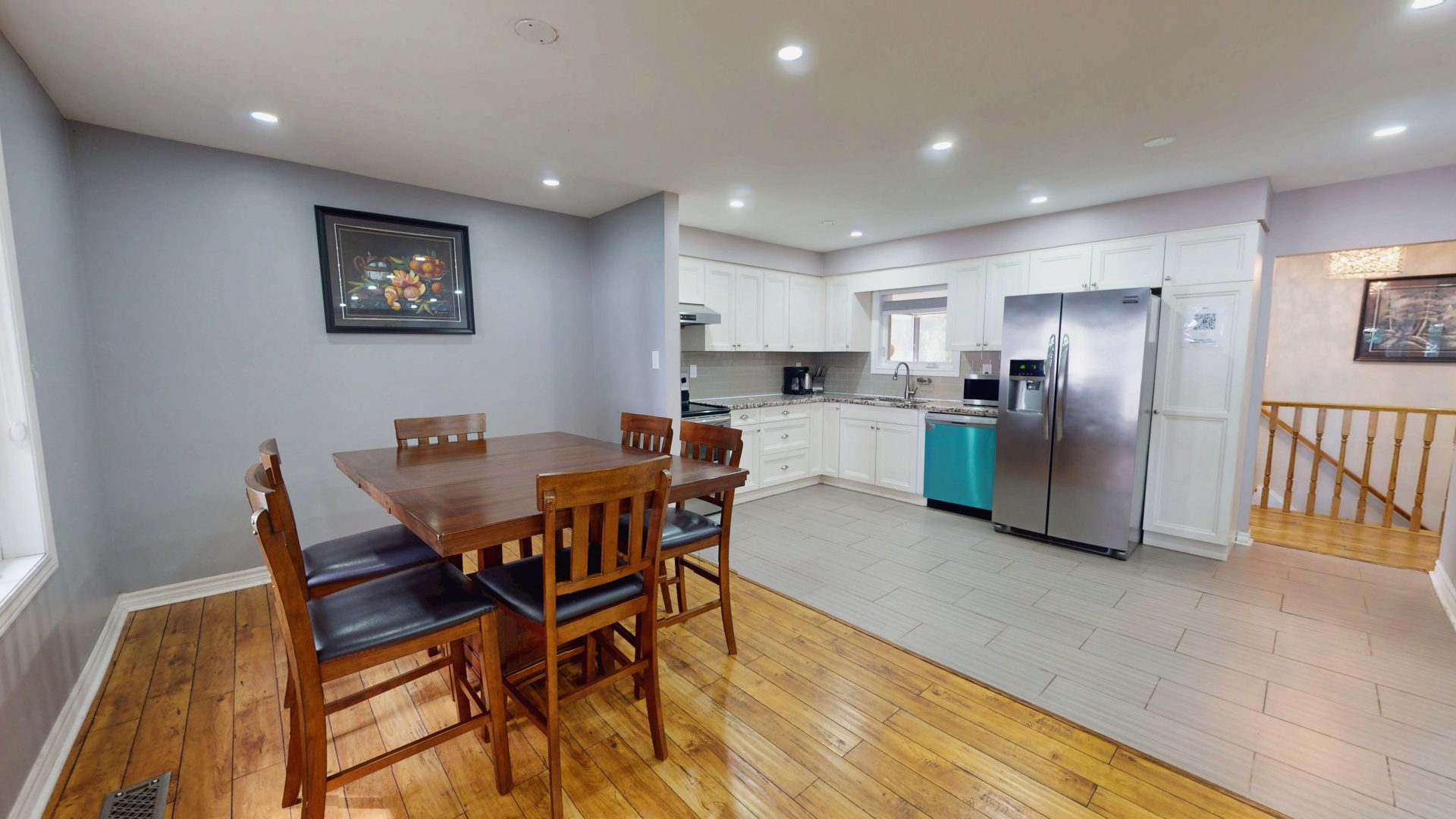 A wood dining table next to a white and grey kitchen